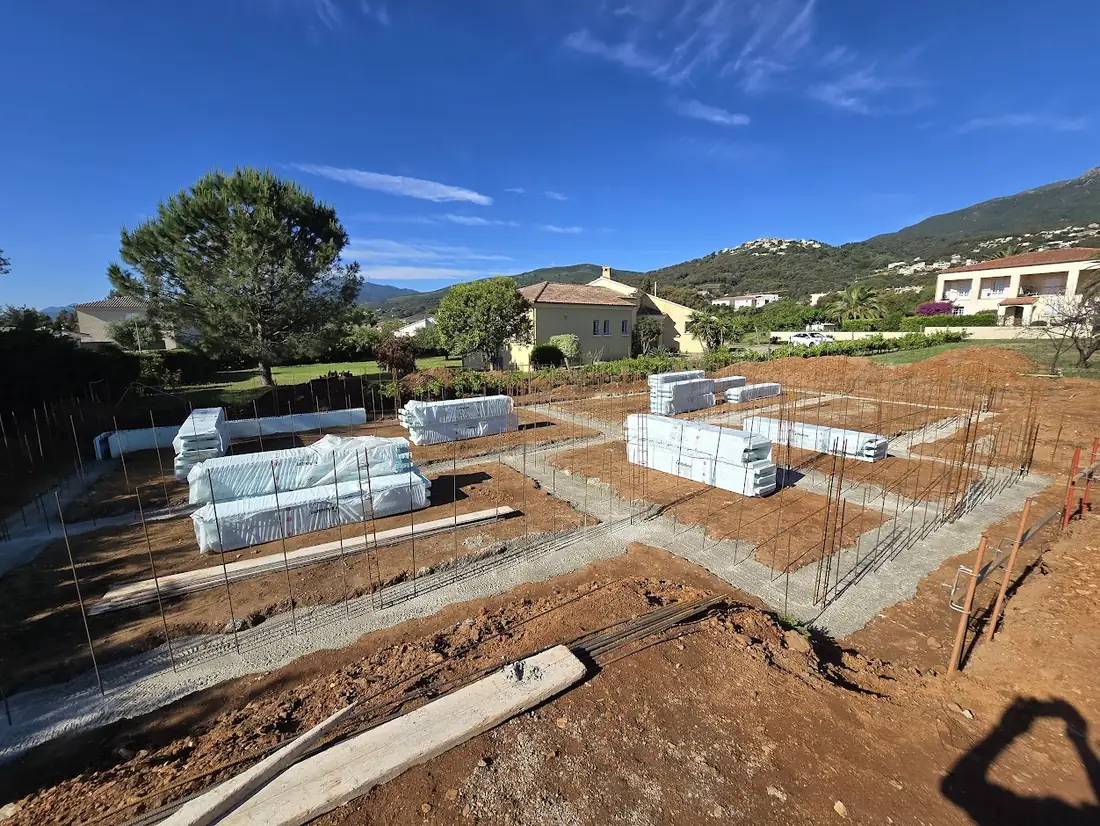 Semelles de fondation ferraillées à Borgo, blocs Nudura livrés et stockés sur le terrain