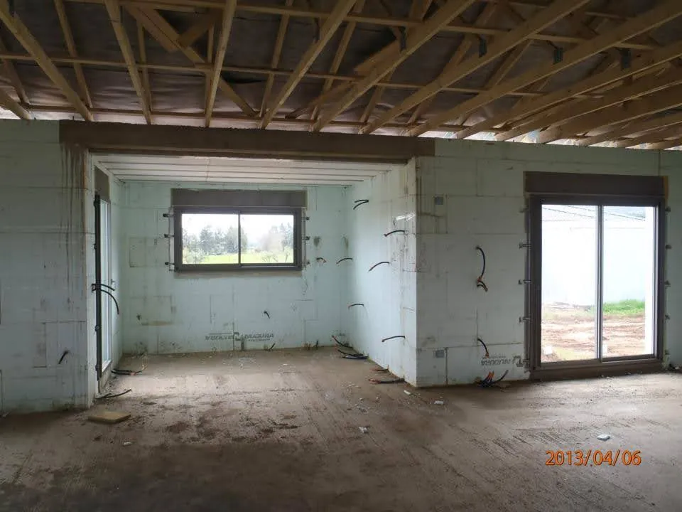 Intérieur d'une villa à Vescovato mise hors d'eau : murs Nudura bruts, linteau, menuiseries posées et charpente en fermettes